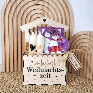 May include: A wooden box with the text "zauberhafte Weihnachtszeit" contains four white candles with festive designs, a purple package, and a gift tag. The box is decorated with stars and a scalloped edge.