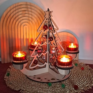 Könnte beinhalten: Ein hölzerner Weihnachtsbaum-Kerzenhalter mit roten und goldenen Ornamenten. Der Baum ist von vier Kerzenhaltern mit brennenden roten Kerzen umgeben. Die Szene befindet sich auf einer gewebten Matte mit dekorativen Elementen.