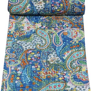 Puede incluir: Un edredón paisley azul enrollado, con un patrón vibrante. El edredón presenta grandes diseños de cachemira en forma de lágrima en tonos de azul, verde, naranja y blanco. El edredón está hecho de un material suave y probablemente está cosido a mano.