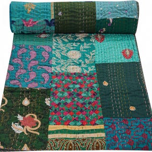 Könnte beinhalten: Ein Patchwork-Quilt in Türkis, Grün und Gold mit aufwendigen Stickereien mit Blumen- und Paisley-Mustern. Der Quilt ist oben aufgerollt und zeigt die Vielfalt der Muster und Texturen. Die Nähte sind über den gesamten Quilt sichtbar.