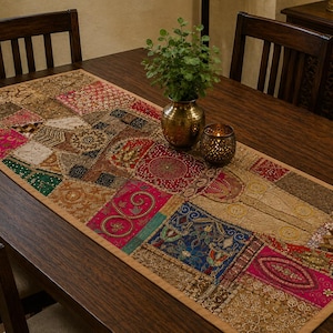May include: A rectangular table runner featuring a patchwork design of various fabric squares in shades of red, blue, green, and gold. The runner is decorated with intricate embroidery, metallic thread work, and small sequins throughout the surface.
