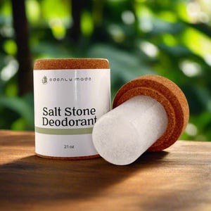 May include: A white cylindrical container of salt stone deodorant with a cork lid, next to a salt stone. The label reads "edenly made" and "Salt Stone Deodorant". The product is 2.1 oz.