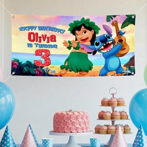 May include: A birthday banner featuring Lilo and Stitch with the text "Happy Birthday Olivia is Turning 3". The banner has a beach scene background with a ukulele. A pink cake and cupcakes are on display.