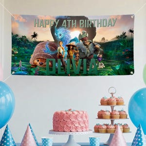 May include: A banner with the text "HAPPY 4TH BIRTHDAY OLIVIA" featuring characters from a movie. The banner is hung above a table with a pink cake, cupcakes, party hats, and balloons. The cake has a spiral rose design.