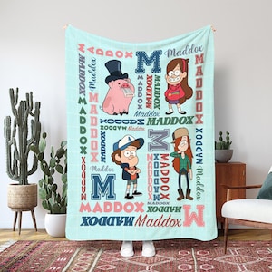 Könnte beinhalten: Eine hellblaue Decke mit Cartoon-Charakteren und dem Namen "Maddox" in verschiedenen Schriftarten und Farben. Die Decke hat einen Hintergrund mit Gittermuster und enthält Illustrationen eines Schweins mit Zylinder, eines Mädchens mit Zahnspange, eines Jungen mit Mütze und eines Mädchens mit langen Haaren.