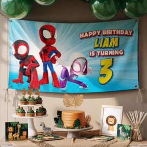 Op de afbeelding: Een verjaardagsfeestje met een banner met Spider-Man-personages. Op de banner staat "Happy Birthday Liam is turning 3." Een taart, cupcakes en jungle-thema decoraties worden getoond.