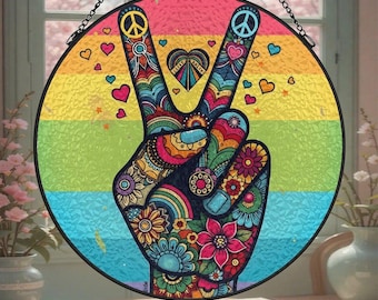 May include: A circular suncatcher featuring a vibrant rainbow-striped background and a central hand making a peace sign. The hand is decorated with intricate, colorful floral and geometric patterns, including small hearts and peace symbols.
