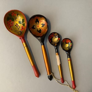 May include: Four wooden spoons with black and gold painted designs. The spoons have red tips and feature floral patterns.