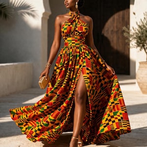 May include: A floor-length halter neck dress featuring a vibrant geometric pattern in red, yellow, green, and black. The dress has a fitted bodice, a defined waistline, and a full, flowing skirt with a high front slit that reveals the leg.