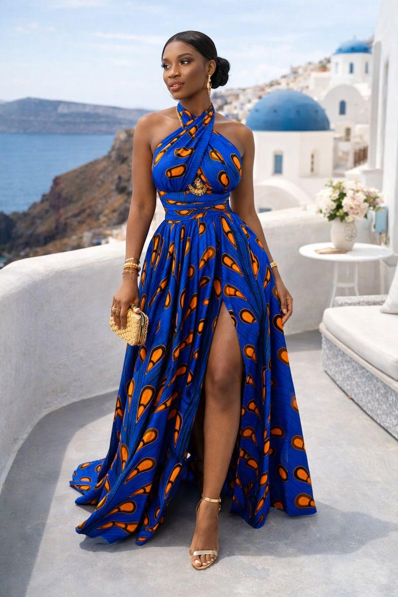 May include: A floor-length blue dress featuring a vibrant orange and black teardrop pattern, a halter neckline with a crisscross bodice, and a high side slit. The garment includes a fitted waist and a flowing, pleated skirt that reaches the floor.