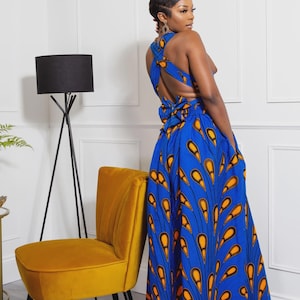 May include: A floor-length blue dress featuring a vibrant orange and black peacock feather-inspired pattern. The garment has a sleeveless bodice with a crisscross back design, a tie-waist detail, and a full, flowing skirt with side pockets.