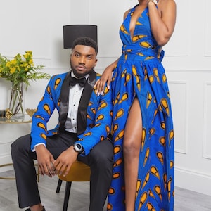 May include: A blue blazer with a black satin shawl collar and a matching floor-length halter dress, both featuring a vibrant yellow and orange teardrop pattern. The blazer is paired with a white button-down shirt, black bowtie, and black trousers.