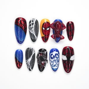 May include: A set of ten artificial nails with a Spider-Man theme. Designs include a web, the Spider-Man mask, and the words "Go Spider Go". The nails feature red, blue, black, white, and yellow colors.