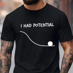 Könnte beinhalten: Eine weiße Keramik-Tasse mit schwarzem Henkel und dem Text "But First, Coffee" in fetter, schwarzer Schrift. Die Tasse steht vor einem verschwommenen Hintergrund, der eine gemütliche Umgebung suggeriert.