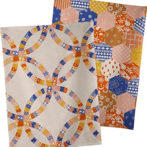 May include: Two rectangular kitchen towels featuring textile patterns. One towel displays a cream background with interlocking rings in orange, blue, and pink. The second towel features a multi-colored hexagonal patchwork design with floral, hand, and geometric motifs.