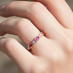 Peut inclure: Bague en or rose ornée de pierres précieuses rouges en forme de marquise et de pierres rondes et transparentes. La fine monture met en valeur l'éclat des pierres. Vue rapprochée du design complexe de la bague.