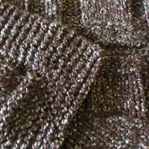 May include: Close-up of a brown and white knitted fabric with a textured, speckled pattern.
