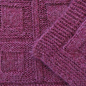 May include: Close-up of a knitted fabric with a textured pattern. The fabric is a deep purple color.