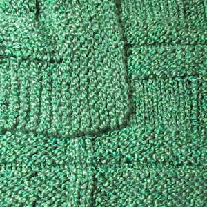 May include: Green knitted fabric with a woven pattern. The fabric has a textured surface and a slightly iridescent sheen.