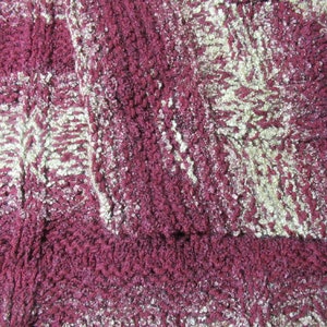 May include: Close-up of a burgundy and gold fabric with a textured, woven pattern.