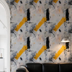 May include: Wallpaper featuring an abstract design with bold yellow diagonal brushstrokes, black ink splatters, and soft grey patches on a light background. The pattern creates a layered, artistic effect across the wall surface.