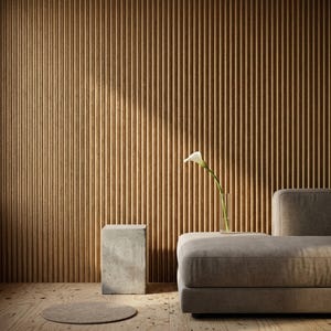 May include: A contemporary interior with a light brown, vertically-lined wall and wooden floor. A grey sofa and a concrete side table are featured. A white calla lily in a glass vase adds a touch of elegance to the scene.