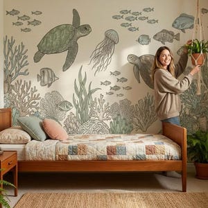 Puede incluir: Un dormitorio con una cama de madera, una alfombra de yute y un mural que representa criaturas marinas. El mural incluye tortugas, peces y medusas. Una mujer sostiene una planta en maceta. Arte de animales enmarcados cuelga en la pared.