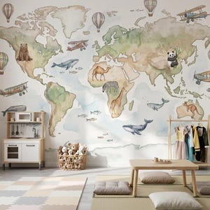 Op de afbeelding: Een kinderkamer met een muurschildering van een wereldkaart in aquarel met illustraties van dieren, vliegtuigen en luchtballonnen. De kamer heeft een speelkeuken, een kledingrek, een kleine tafel en een mand met knuffels. De vloer heeft een kleurrijke puzzelmat.