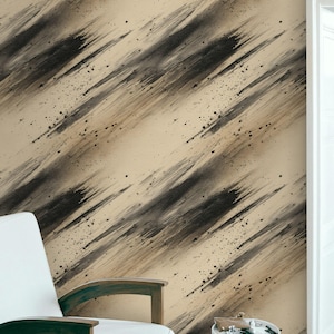 Puede incluir: Papel pintado abstracto con pinceladas negras diagonales y salpicaduras sobre un fondo beige. Una silla blanca con brazos de madera y una pequeña mesa auxiliar están en primer plano, lo que sugiere un tema de diseño de interiores moderno.