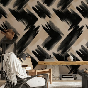 May include: A room featuring wallpaper with a beige and black abstract brushstroke design. The room is furnished with a wicker chair, a wooden shelf, and a small table. Decorative items include a vase, books, and a sculpture.