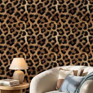 May include: Leopard print wallpaper featuring a repeating pattern of brown and black spots. The wallpaper is behind a cream armchair, a wooden side table, a lamp, and decorative cushions.