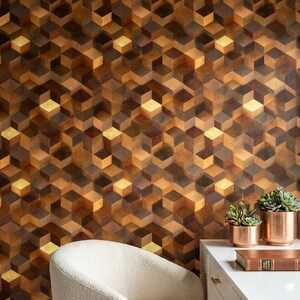 May include: A white desk with two copper-colored pots containing green succulents and a brown book, positioned next to a cream-colored upholstered chair. The wall features wallpaper with a repeating geometric pattern of brown and gold cubes.