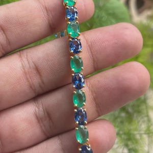 Può includere: Bracciale in oro con smeraldi e zaffiri ovali alternati. Le pietre preziose sono incastonate in una catena d'oro, creando un vibrante contrasto di tonalità verdi e blu. Il bracciale è progettato per un look classico ed elegante.