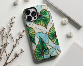 May include: A smartphone case with a leaf design. The case features green leaves with gold outlines against a light blue and white background. The case has a black camera module and the brand name "SABLE & STITCH CO." is printed at the bottom.