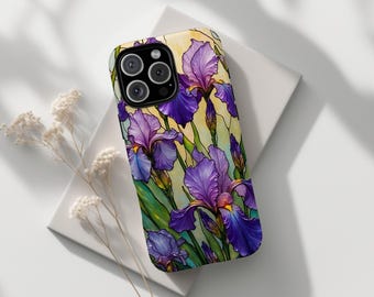 Puede incluir: Una funda de teléfono con un diseño de vidriera que representa lirios morados con hojas verdes y un fondo amarillo. La funda tiene un módulo de cámara negro. El texto "SABLE & STITCH CO." está en la parte inferior.