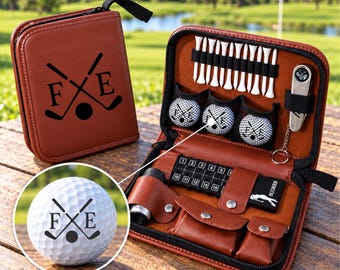Könnte beinhalten: Ein Golf-Zubehörset aus braunem Kunstleder mit einem Reißverschluss-Etui, auf dem die Buchstaben F und E sowie gekreuzte Golfschläger abgebildet sind. Das offene Etui enthält weiße Golftees, drei Golfbälle, ein Werkzeug und einen Zähler.