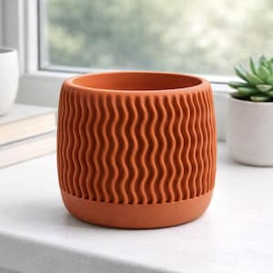Puede incluir: Una maceta de cerámica color terracota con un diseño ondulado y texturizado. La maceta está sobre un alféizar blanco junto a una maceta blanca pequeña con una suculenta y una taza de cerámica blanca. Decoración del hogar.