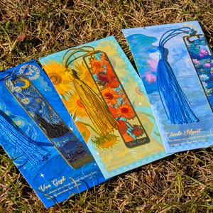 Puede incluir: Cuatro marcadores decorativos con impresiones de arte famosas. Los marcadores tienen borlas coloridas y est&aacute;n tematizados con pinturas de Van Gogh y Claude Monet. Los marcadores est&aacute;n sobre hierba.