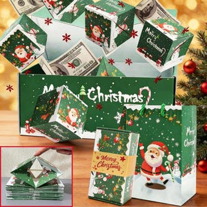 Puede incluir: Una caja de regalo navideña verde y blanca con diseños de Papá Noel, copos de nieve y la frase "Merry Christmas". Contiene cubos de papel plegados y billetes de dólar, sugiriendo un regalo festivo y original.