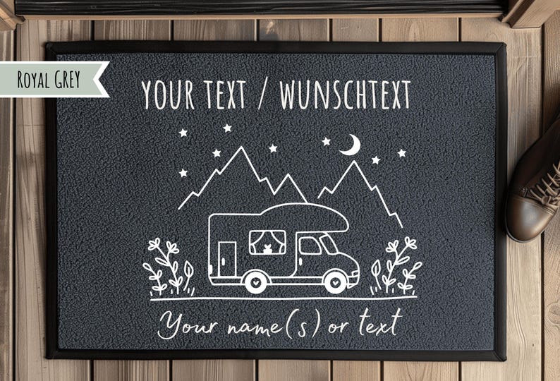 Puede incluir: Felpudo gris real con borde negro. El felpudo presenta una ilustraci&oacute;n blanca de una autocaravana, monta&ntilde;as, estrellas y una luna creciente. El texto dice "YOUR TEXT / WUNSCHTEXT" y "Your name(s) or text".