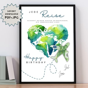 May include: A framed print with a white background features a watercolor heart-shaped world map in shades of green and blue. The words "Happy Birthday" are written below the map, with German text above. A paper airplane made of a 100 Euro note is also included.