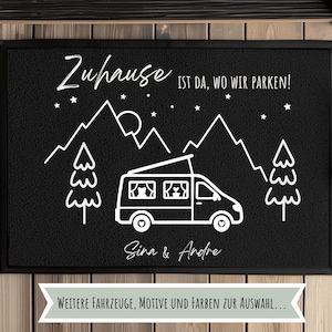 Könnte beinhalten: Schwarze Fußmatte mit weißer Illustration eines Wohnmobils, Bergen, Bäumen und dem Text "Zuhause ist da, wo wir parken!" und "Sina & Andre". Die Matte hat auch den Text "WEITERE FAHRZEUGE, MOTIVE UND FARBEN ZUR AUSWAHL..."