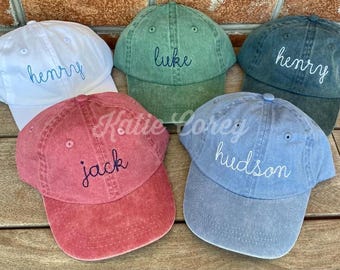 May include: Five personalized baseball caps in different colors. The caps are embroidered with the names "Henry", "Luke", "Jack", "Hudson", and "Henry".