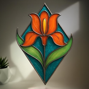 Puede incluir: Panel de vidriera con una flor naranja estilizada con centro amarillo, sobre un fondo turquesa en forma de diamante. La flor tiene hojas verdes y está enmarcada con un borde de metal oscuro. Pieza de arte decorativa.