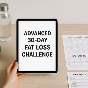 Könnte beinhalten: Ein Tablet zeigt "ADVANCED 30-DAY FAT LOSS CHALLENGE" in schwarzem Text. Graue Kurzhanteln, eine klare Wasserflasche und gedruckte Trainings- und Essenspläne liegen auf einer hellen Holzoberfläche. Das Tablet wird von einer Person gehalten.