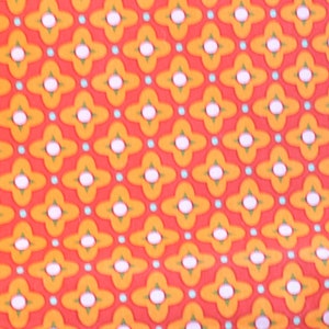 May include: A repeating pattern of orange, white, and blue geometric shapes. The pattern is made up of four-pointed stars with white centers and orange outlines. The stars are surrounded by small blue circles.