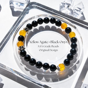 Puede incluir: Un brazalete con cuentas alternas de ónix negro y ágata amarilla. El brazalete está acentuado con elementos decorativos plateados. El texto en la imagen dice: "Yellow Agate • Black Onyx, AAA Grade Beads, Original Design."