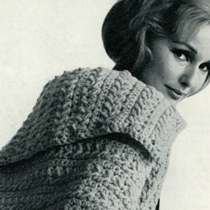 May include: A close-up of a woman wearing a crocheted hooded cardigan. The cardigan is made with a textured stitch and has a wide, open collar.