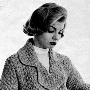 May include: A woman wearing a knitted cardigan with a collar. The cardigan is a light gray color and has a textured pattern. The woman is looking down and has short, blonde hair.