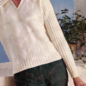 Puede incluir: Su&eacute;ter de punto color crema con cuello en V y patr&oacute;n de diamantes. Las mangas son acanaladas y el su&eacute;ter se combina con pantalones verde oscuro. La imagen es una ilustraci&oacute;n de moda vintage.